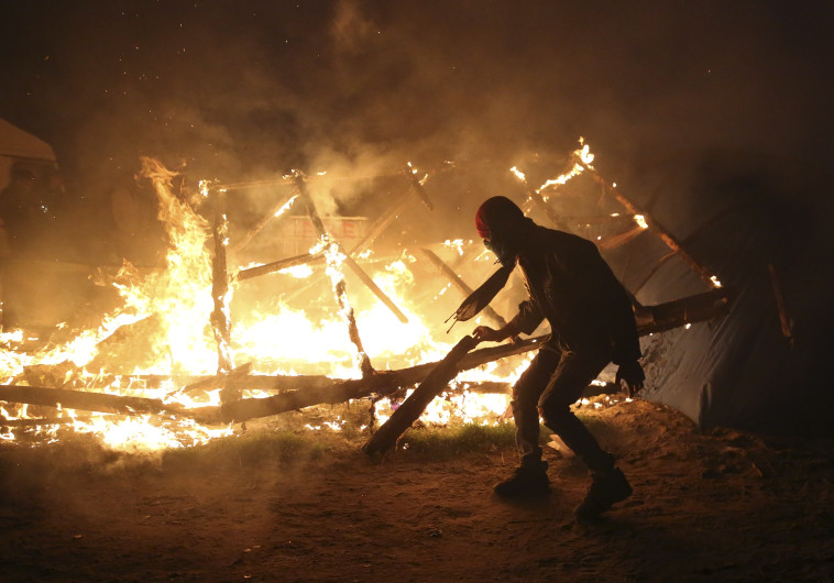 מהגר במהומות במהלך נסיונות הפינוי של מחנה המהגרים הג'ונגל בצרפת. צילום: רויטרס