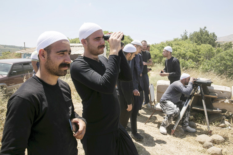 דרוזים בצד הישראלי של הגבול משקיפים על הלחימה בכפר הדרוזי חאדר בצד הסורי. צילום: רויטרס