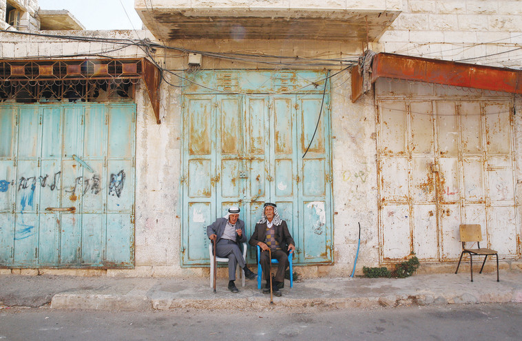 עיר סגורה. פלסטינים ברחוב השוהדא הסגור. צילום: רויטרס