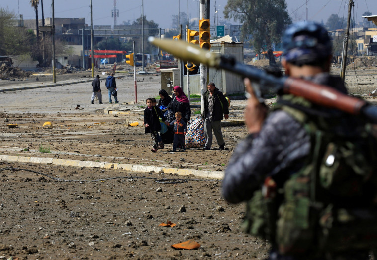 חייל צבא עיראק במוסול צופה במשפחה שבורחת מהעיר. צילום: רויטרס