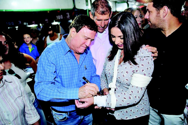 יהורם גאון חותם על הגבס של מירי רגב בשבוע הספר. צילום: אבשלום ששוני