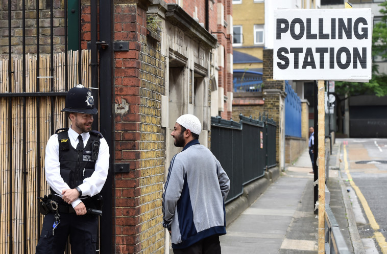 מצביע מוסלמי לצד שוטר בריטי סמוך לקלפי. צילום: רויטרס