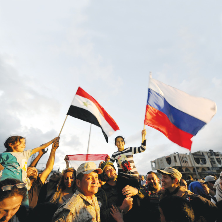 אזרחים חוגגים עם דגלי סוריה ורוסיה בחומס. צילום: רויטרס 