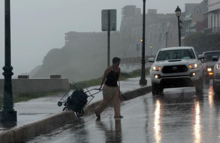 הוריקן אירמה משתולל בפורטו ריקו בעוד הולכת רגל מנסה לחצות את הכביש. צילום: רויטרס