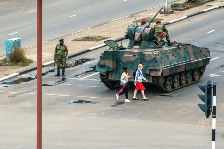 נערות חולפות ליד טנק בזימבבואה