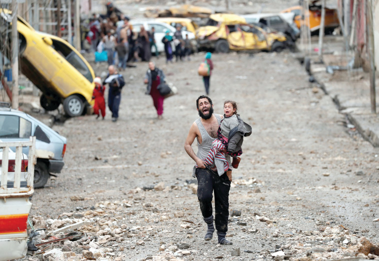 אב נושא את בתו בזמן קרב בין כוחות דאע&quot;ש לצבא עיראק במוסול