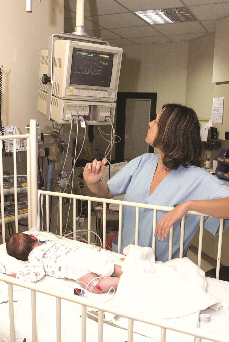 &quot;לא הבנו מה הבעיה עד שהגענו לבית החולים, שם היו עוד תינוקות עם אותם תסמינים&quot;. אחות בבית החולים שניידר מטפלת בתינוק נפגע רמדיה, 2003. צילום:  ברקאי וולפסון 