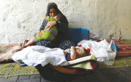אישה פלסטינית עם ילדיה בעזה (צילום: רויטרס)