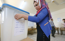 עובדת מכינה את עמדת ההצבעה למשאל העם הכורדי בעיראק (צילום: אלי דסה)