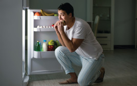 גבר אוכל מול המקרר בלילה, אילוסטרציה (צילום: אינג אימג')