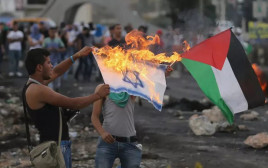 מפגינים פלסטינים שורפים דגל ישראל ליד בית אל  (צילום: רויטרס)