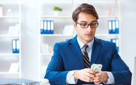 גבר בחליפה מחזיק כסף, צילום אילוסטרציה