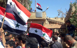 הנפת דגלי סוריה בדרעא (צילום: AFP)