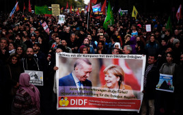 מפגינים מניפים שלט בו כתוב "די לתמיכה הגרמנית בארדואן" (צילום: AFP)
