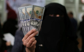 עובדת חמאס בעזה מציגה דולרים לאחר שקיבלה משכורת מקטאר (צילום: רויטרס)