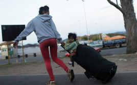 אישה המבקשת לחצות את הגבול מוונצואלה לברזיל לוקחת עמה את בנה על מזוודה (צילום: רויטרס)