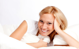 אישה מחייכת במיטה (צילום: אינג אימג')