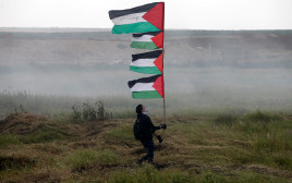 מפגינה נושאת דגל פלסטין בהפרעות סדר, גבול רצועת עזה, 30 במרץ 2018 (צילום: רויטרס)