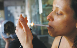 אישה מדליקה סיגריה בתל אביב - ארכיון - צילום רויטרס (צילום: רויטרס)