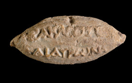 שמות האלים הרקלס והאורונאס על גבי הקליע (צילום: דפנה גזית, רשות העתיקות)