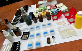 הבקבוקים עם חומר החשוד כסם אונס, הכסף והטלפונים שנמצאו בדירתו של החשוד בתל אביב (צילום: דוברות המשטרה)