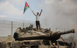 פלסטיני מניף דגל אש"ף מעל טנק ישראלי. מבצע "חרבות ברזל" (צילום: יוסוף מוחמד, פלאש 90)