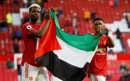 שחקן מנצ'סטר יונייטד פול פוגבה עם אמאד דיאלו מניפים את דגל פלסטין לאחר המשחק מול פולהאם (צילום: רויטרס)