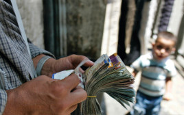 מחליף מטבעות פלסטיני סופר כסף ברחוב ברמאללה  (צילום: רויטרס)