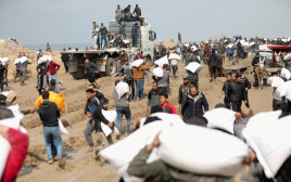 פלסטינים נושאים שקי קמח ממשאית סיוע הומניטארי (צילום: רויטרס)