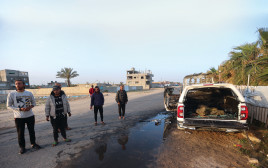 עזתים עומדים ליד רכב ארגון הסיוע שנפגע השבוע בעזה  (צילום: רויטרס)