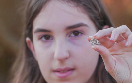 הקמיע שעליו סימן העקרב בידה של דפנה פילשטיינר (צילום: אמיל אלג'ם, רשות העתיקות)