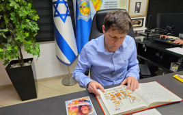 רמי גרינברג עם ספר הזיכרון להנצחת משפחת ביבס (צילום: דוברות העירייה)