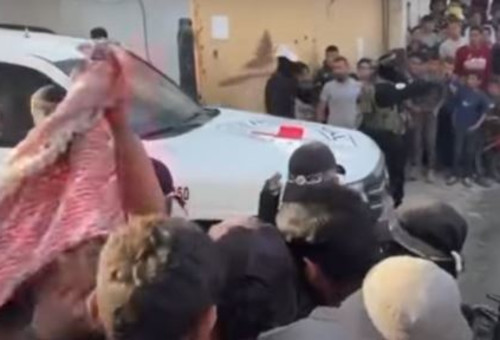 רכבי הצלב האדום ובהם החטופים בין המון עזתי, מאובטחים בידי חמאס (צילום: רשתות ערביות)
