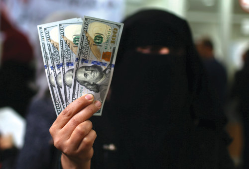 טרוריסט רעול פנים מחזיק כסף דולרים ביד  (צילום: רויטרס)