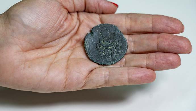 המטבע הנושא את דמותה של לונה, אלת הירח. מתחתיה מופיע סימן מזל סרטן. (צילום: יניב ברמן, רשות העתיקות)