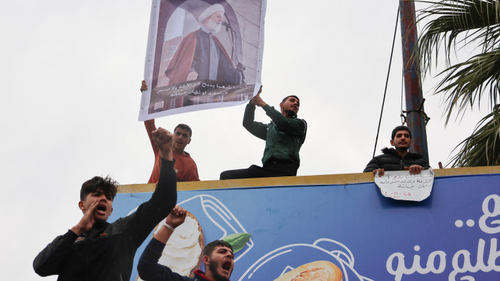 מפגינים עלאווים אוחזים בשלטו של השייח'  ר'זאל ר'זאל