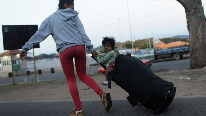 אישה המבקשת לחצות את הגבול מוונצואלה לברזיל לוקחת עמה את בנה על מזוודה