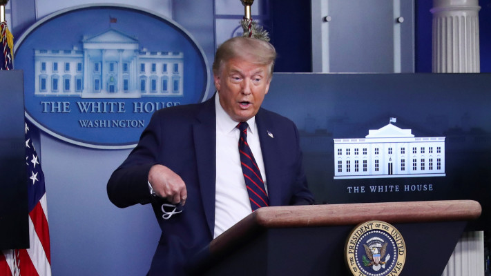 דונלד טרמאפ מחזיק מסכה בזמן תדרוך