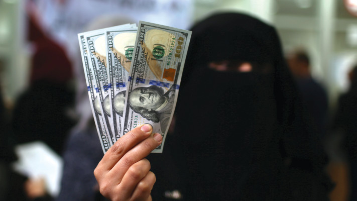 טרוריסט רעול פנים מחזיק כסף דולרים ביד  (צילום: רויטרס)