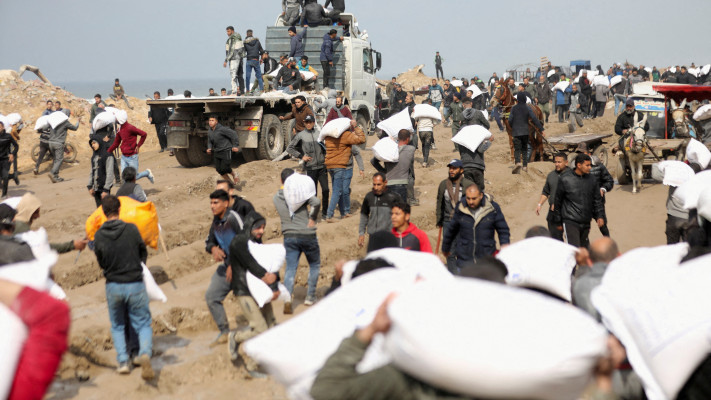 פלסטינים נושאים שקי קמח ממשאית סיוע הומניטארי