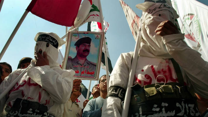 2003. פלסטינים צועדים עם דיוקן של סדאם חוסיין בחאן יונס