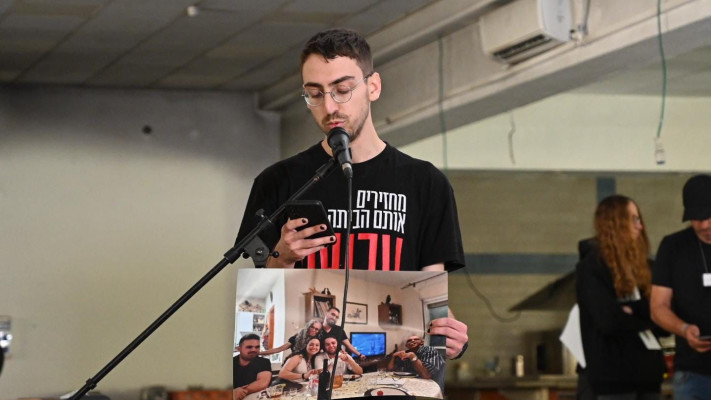 עמיר אלפסה בסדר בחדר האוכל בניר עוז, אוחז בתמונה של דודתו מיה גורן ז''ל ומשפחתה