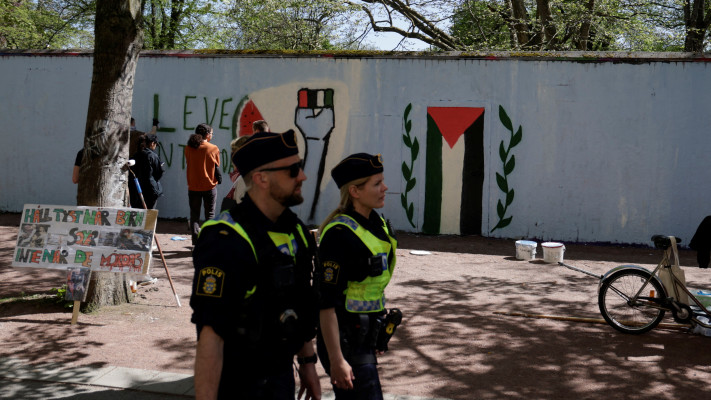 שוטרים שוודים מסתובבים בזמן שפעילים פרו-פלסטינים מציירים ציור קיר במאלמו (צילום: רויטרס)