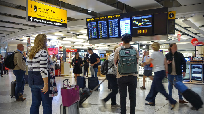 נוסעים מול לוח הטיסות בשדה התעופה בלונדון