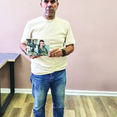 דוד לוי מחזיק בתמונה של דניאל בנו מימין ואחיינו משמאל