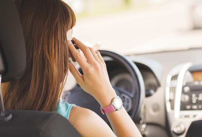 צעירה מדברת בטלפון תוך כדי נהיגה (צילום:  אינג אימג')