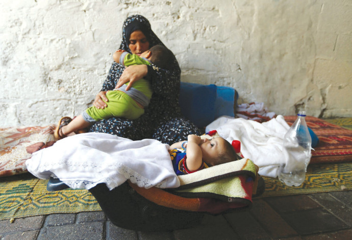 אישה פלסטינית עם ילדיה בעזה (צילום:  רויטרס)
