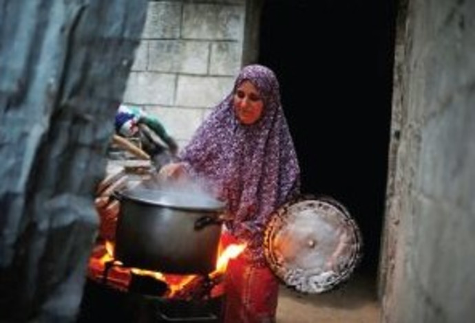 אישה מבשלת במהלך הפסקת חשמל בעזה (צילום:  רויטרס)