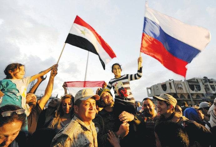 אזרחים חוגגים עם דגלי סוריה ורוסיה בחומס (צילום:  רויטרס)
