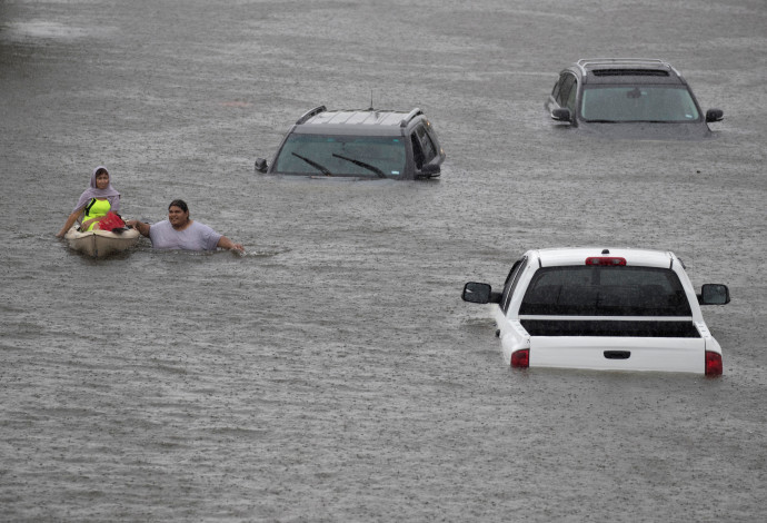 אדם מחלץ אישה במהלך השיטפונות בפאתי יוסטון (צילום:  רויטרס)